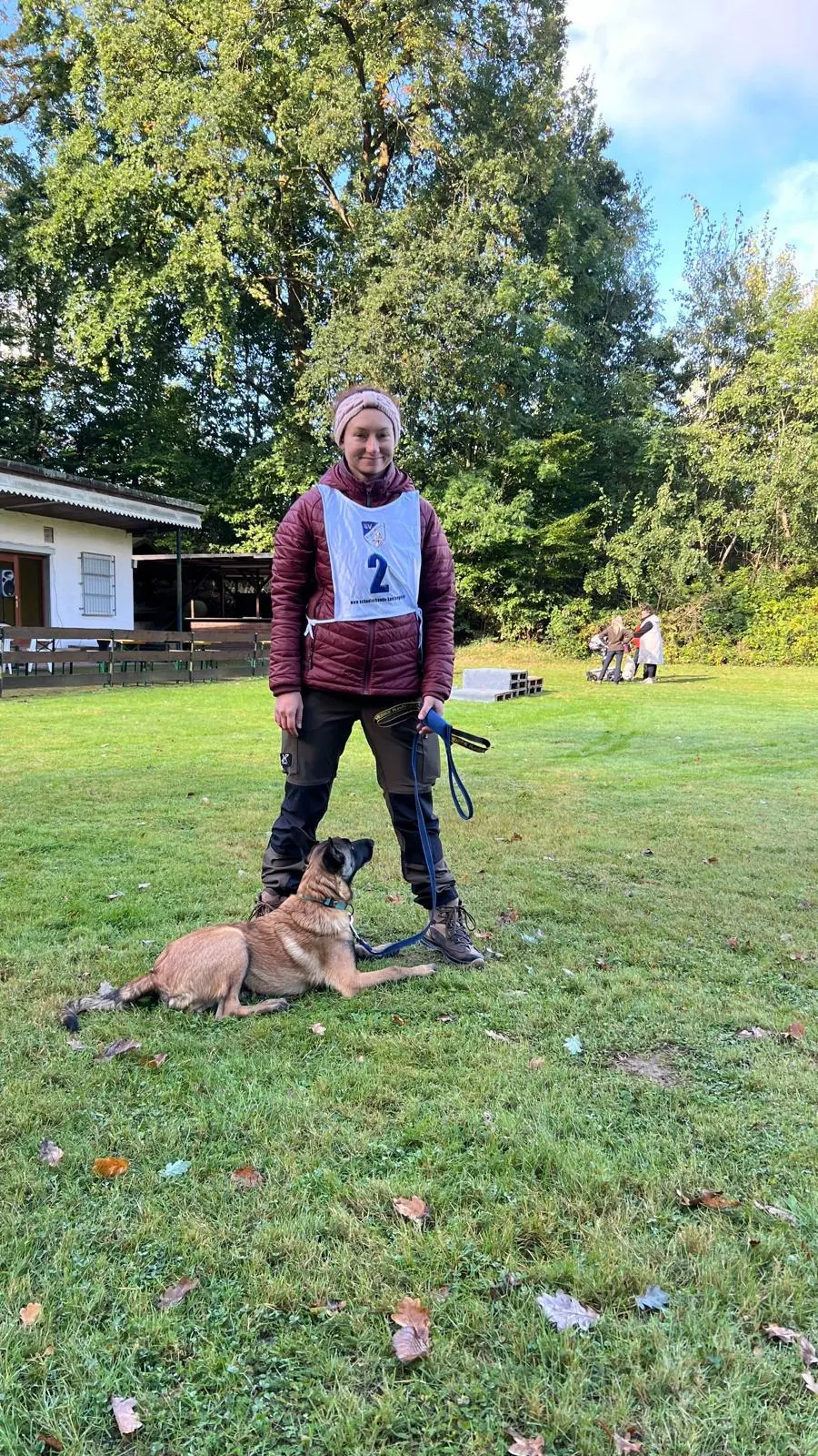 Hundeführerin mit Startnummer und liegendem Hund